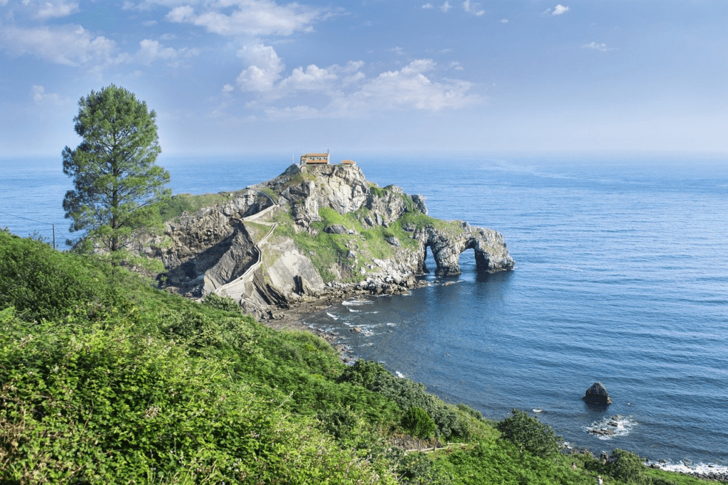 A scenic view of a small house on a hill surrounded by the sea, representing why we let others shape our lives and the path to self-empowerment.